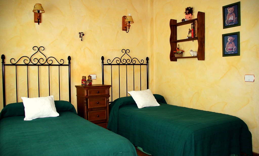 Dormitorio del apartamento con dos camas y colchas verdes