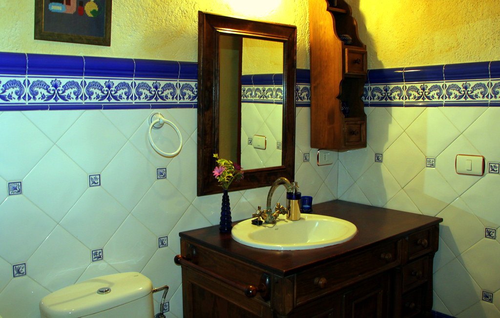 Baño con azulejos canarios y lavabo sobre mueble de madera