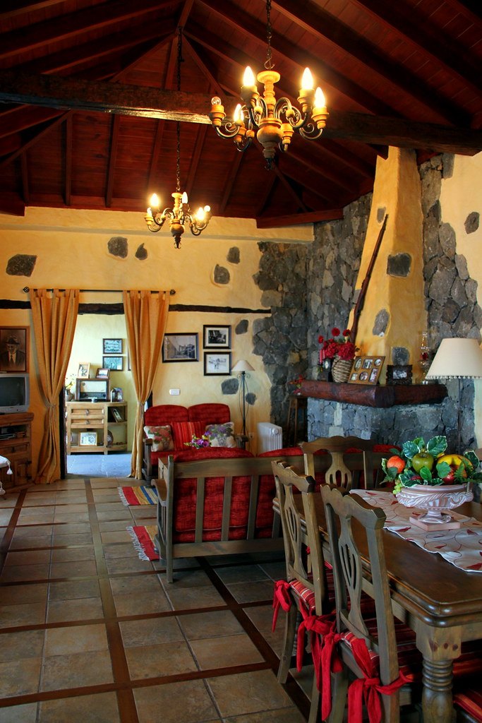 Cocina abierta al comedor con muebles de madera y lámpara de hierro