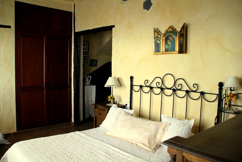 Dormitorio con cama de hierro forjado y paredes amarillas