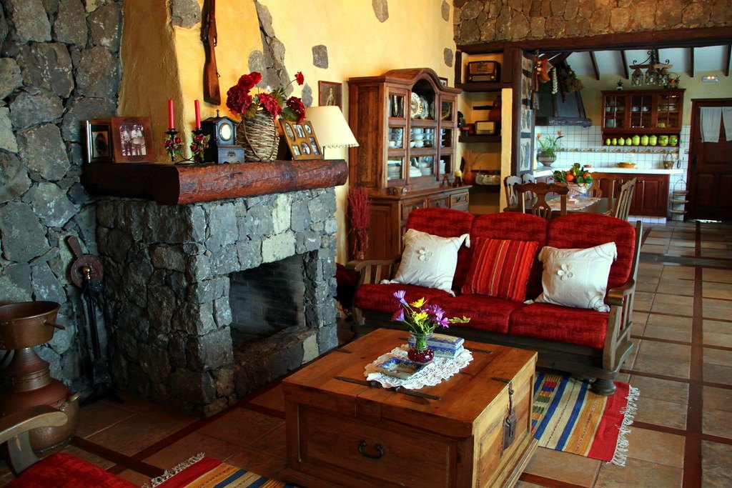 Salón con chimenea de piedra, sofá rojo y muebles antiguos